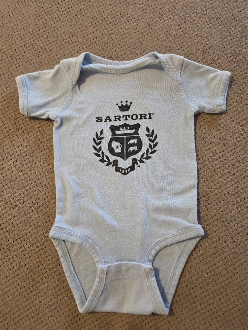light blue infant short-sleeve bodysuit featuring the corporate crest and logo